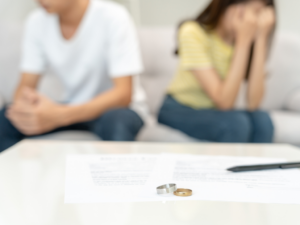 外遇離婚律師協助處理婚姻破裂,前景桌上放著婚戒與離婚協議書