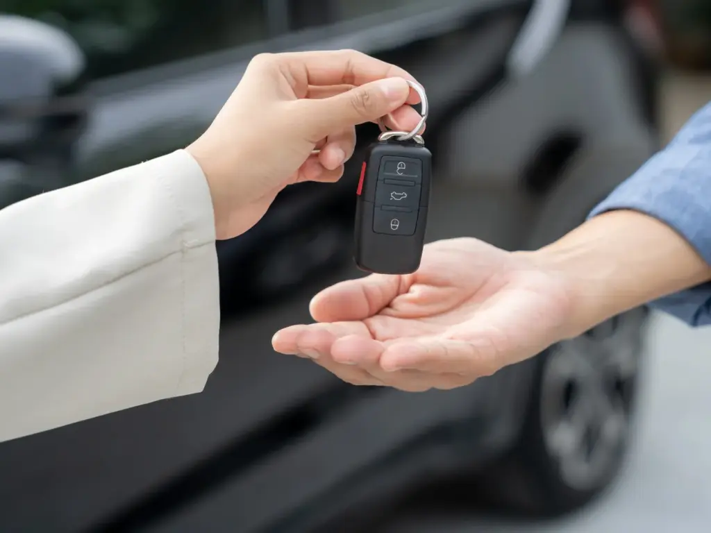 一人在汽車旁將車鑰匙交給另一人