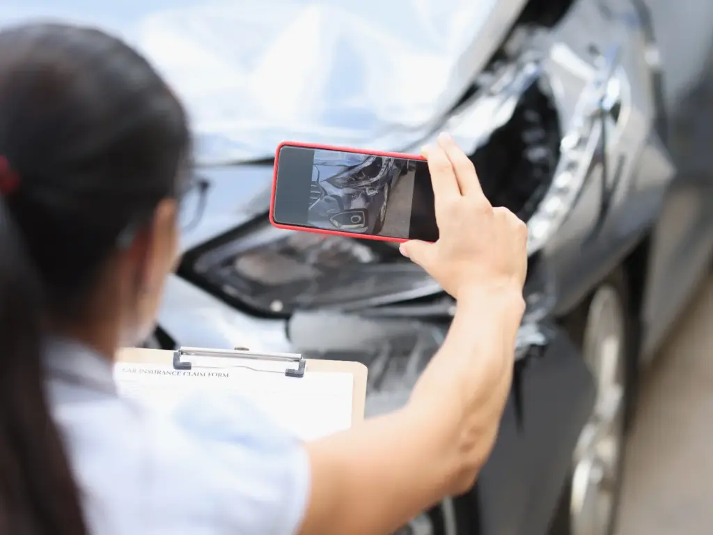駕駛以手機拍攝汽車保險桿擦痕，記錄車輛受損情況